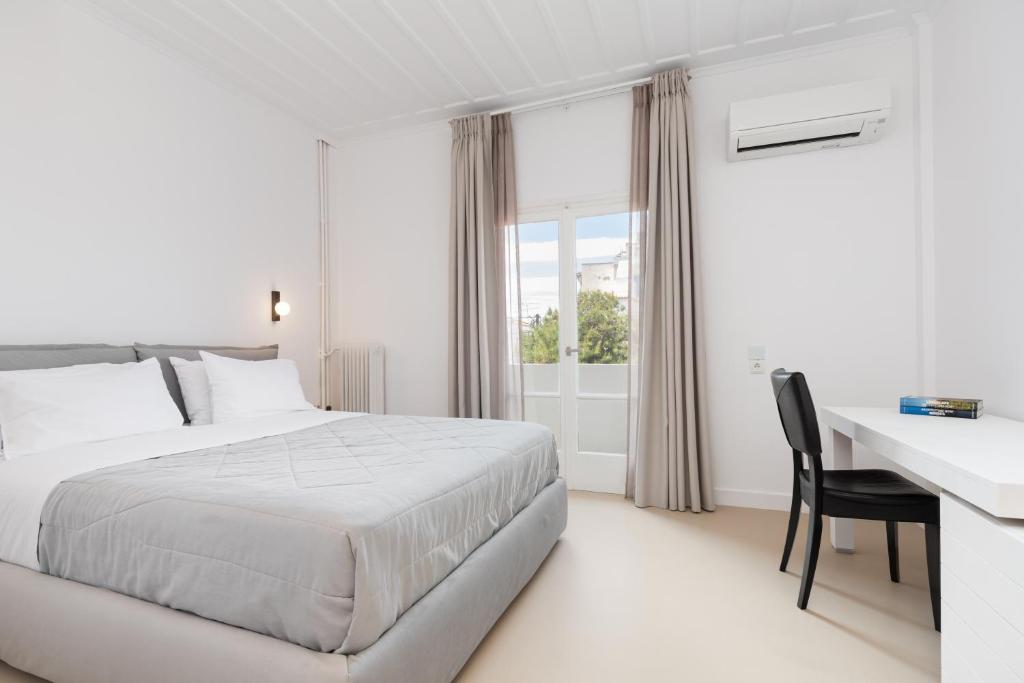 a white bedroom with a bed and a desk at Hotel Roumani in Spetses