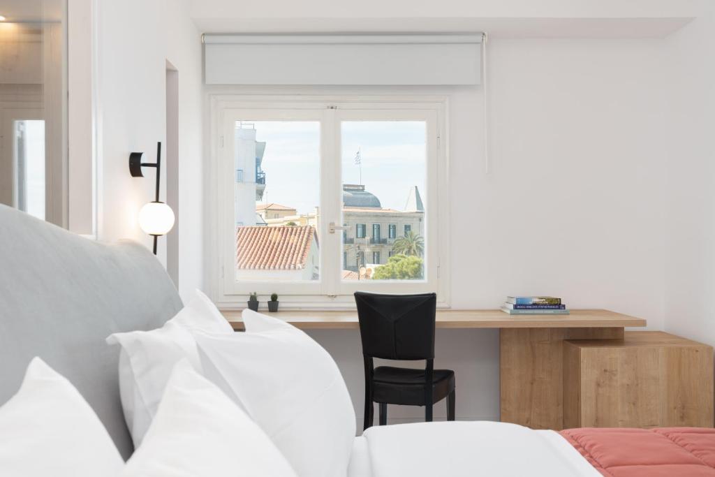 a bedroom with a desk and a chair and a window at Hotel Roumani in Spetses