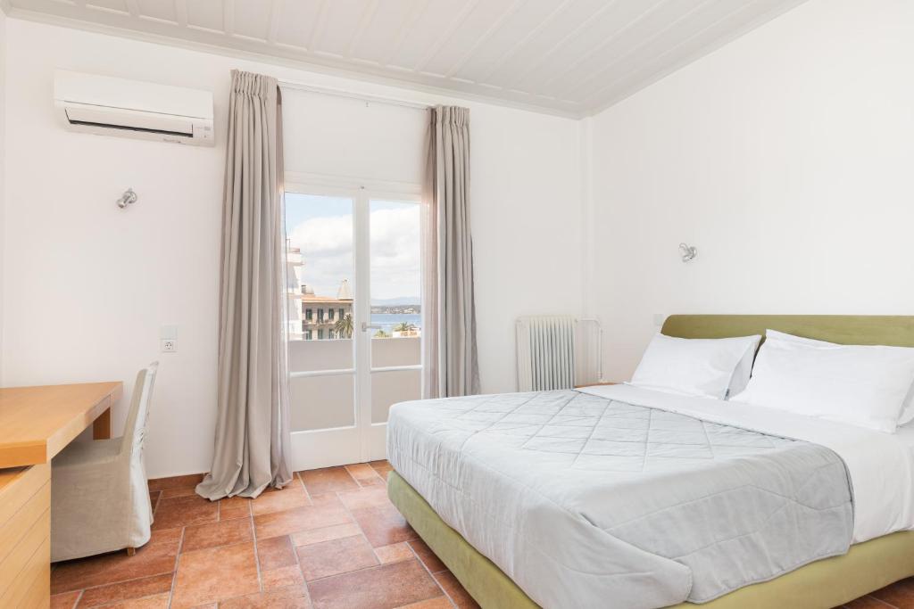 a bedroom with a bed and a desk and a window at Hotel Roumani in Spetses