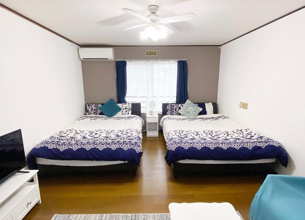 a bedroom with two beds and a ceiling fan at Flat piece chair house - Vacation STAY 40368v in Fuzuchi