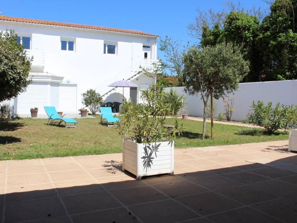 a yard with two chairs and a white building at Maison bord de mer à la Cotinière, 3 chambres, terrasse et parking, 6 couchages - FR-1-246A-101 in Saint-Pierre-dʼOléron