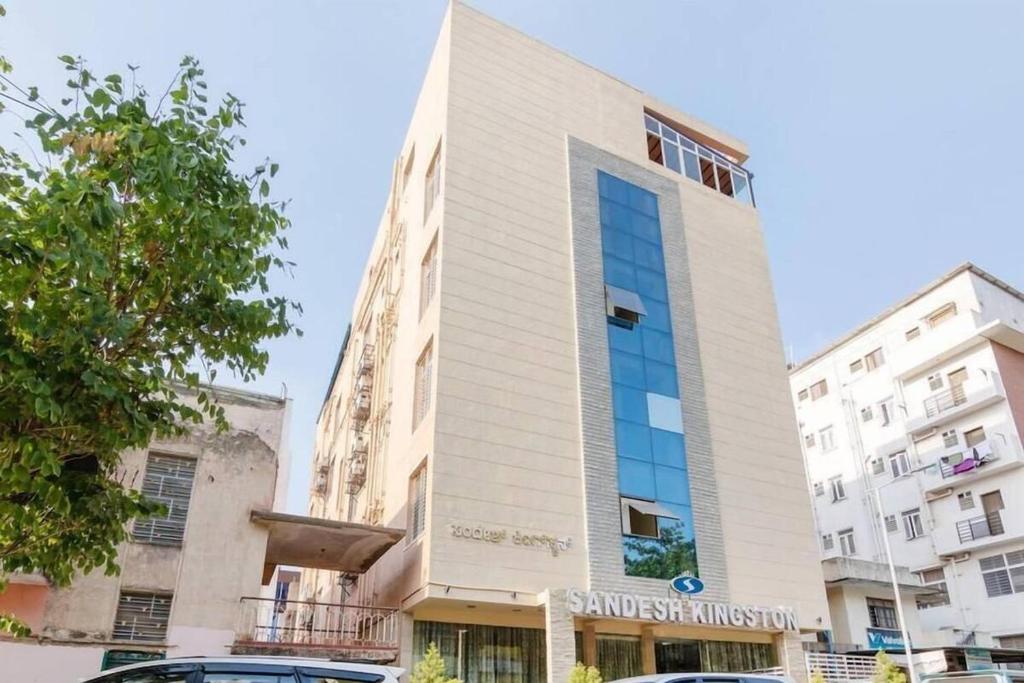 a tall building with cars parked in front of it at Sandesh Kingston in Bangalore
