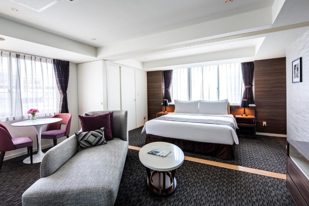 a hotel room with a bed and a couch and a table at Somerset Ginza East Tokyo in Tokyo