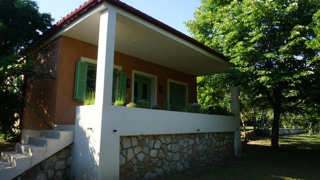 Casa pequeña con pared de piedra y ventanas verdes en KAVET Palio Cottage, en Palaión Tsiflíkion