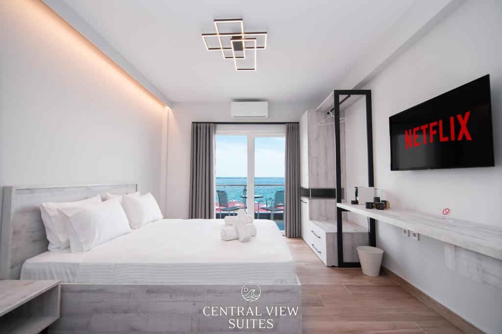 a bedroom with a white bed and a tv at CentralViewSuites in Nea Moudania