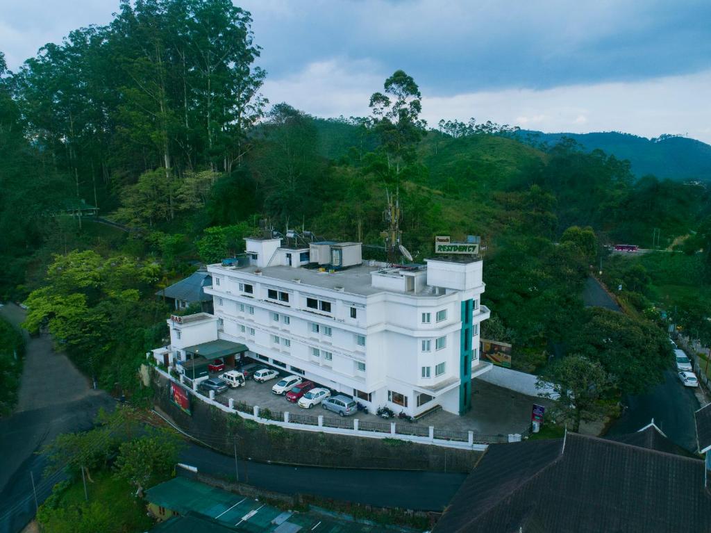 an aerial view of a white building with a parking lot at Issacs Residency in Munnar