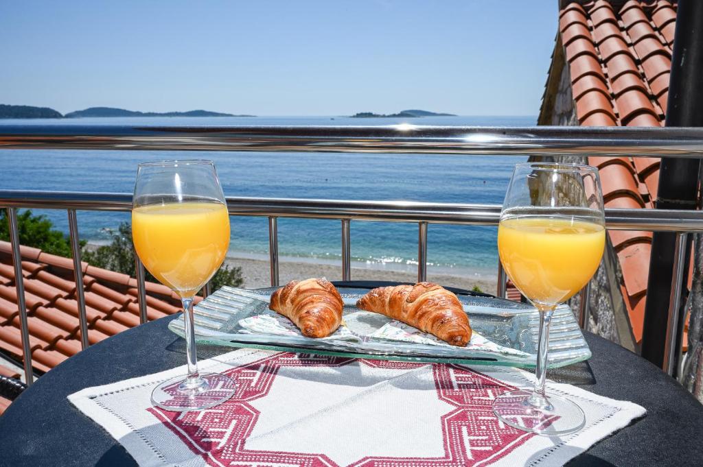 a table with two glasses of orange juice and croissants at Beach House Poseydon in Mlini
