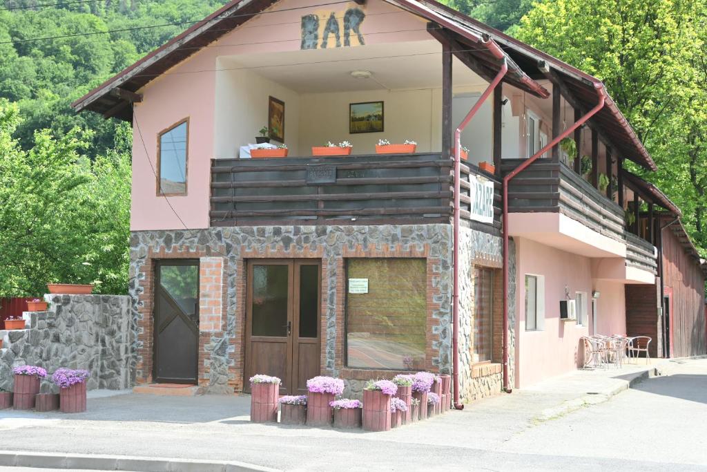 a pink building with a balcony with purple flowers at Casa Luminita in Brezoi