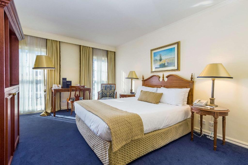 a hotel room with a large bed and two lamps at Quality Hotel Canterbury International in Forest Hill