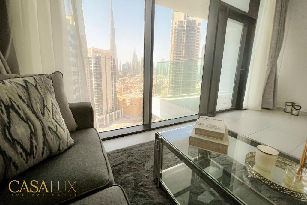 Stunning STD Flat in DT, with Burj Khalifa view . في دبي: غرفة معيشة مع أريكة وطاولة زجاجية