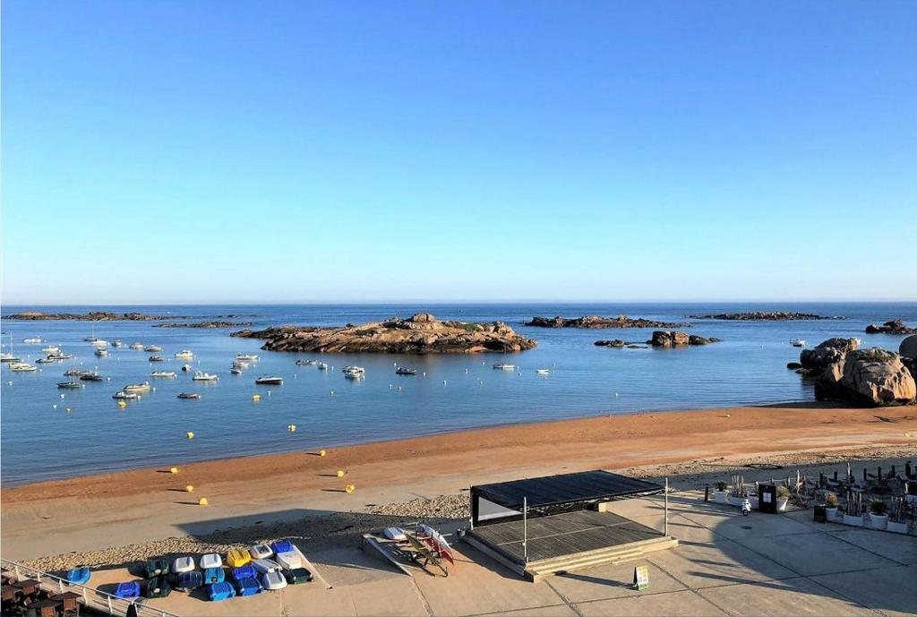 een uitzicht op een strand met boten in het water bij Appartement VUE MER EXCEPTIONNELLE plage du Coz-Pors à TREGASTEL - Ref 721 in Trégastel