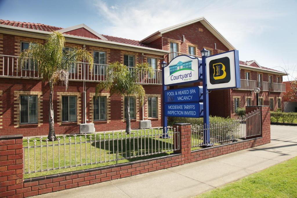 un bâtiment avec un panneau devant une maison dans l'établissement Courtyard Motor Inn, à Shepparton