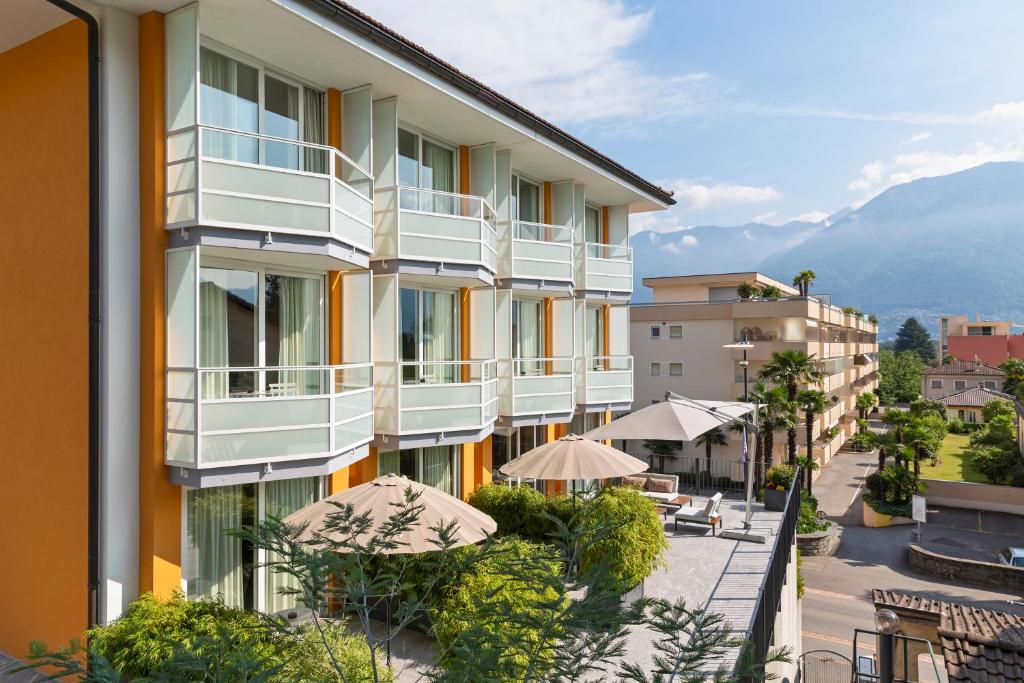 アスコナにあるJazz Hotel Asconaのパラソルとパティオ付きのアパートメントビル