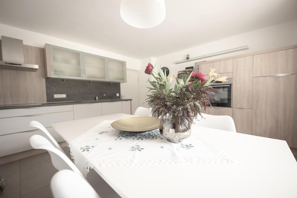 una cocina blanca con una mesa con un jarrón de flores. en Village Charme, en Molini di Tures