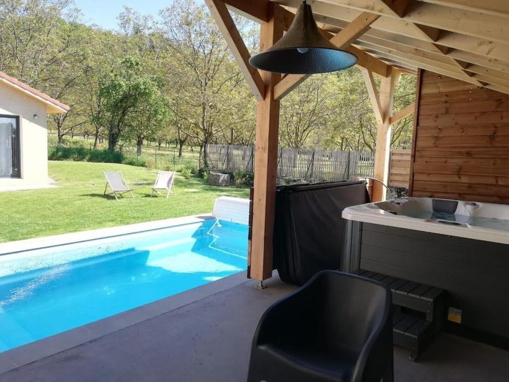 een patio met een zwembad en een tafel en stoelen bij La grange au pied du Vercors Piscine et SPA privatifs in Saint-Romans