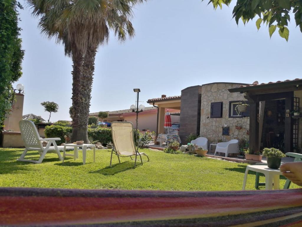 une cour avec des chaises, une table et un palmier dans l'établissement Villa La fenice, à Granelli