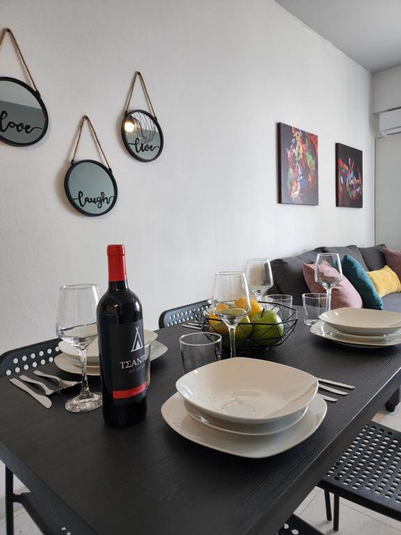 einen schwarzen Tisch mit einer Flasche Wein und Gläsern in der Unterkunft Kay's City & Seaview One Bedroom Apartment in Larnaka