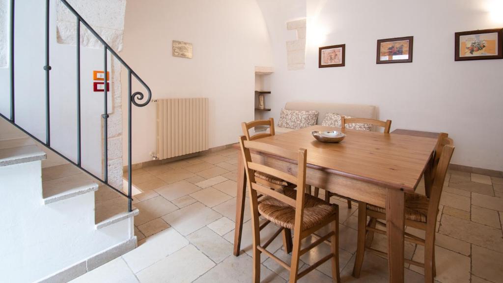 uma sala de jantar com uma mesa de madeira e cadeiras em Casa Colombo & Casa Scipione by Rentbeat em Ostuni