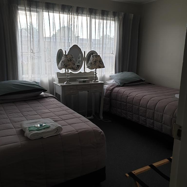 a bedroom with two beds and a mirror and a window at Family friendly unit in Hastings