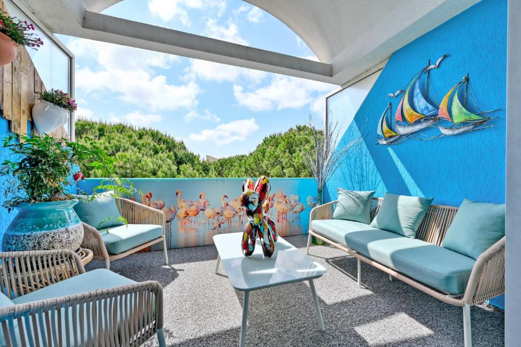 un patio con sofás y una pared azul en T3 de 45 m2 avec terrasse - Entièrement climatisé - 2 chambres - 400m de la plage - résidence avec piscine, en Le Grau-du-Roi