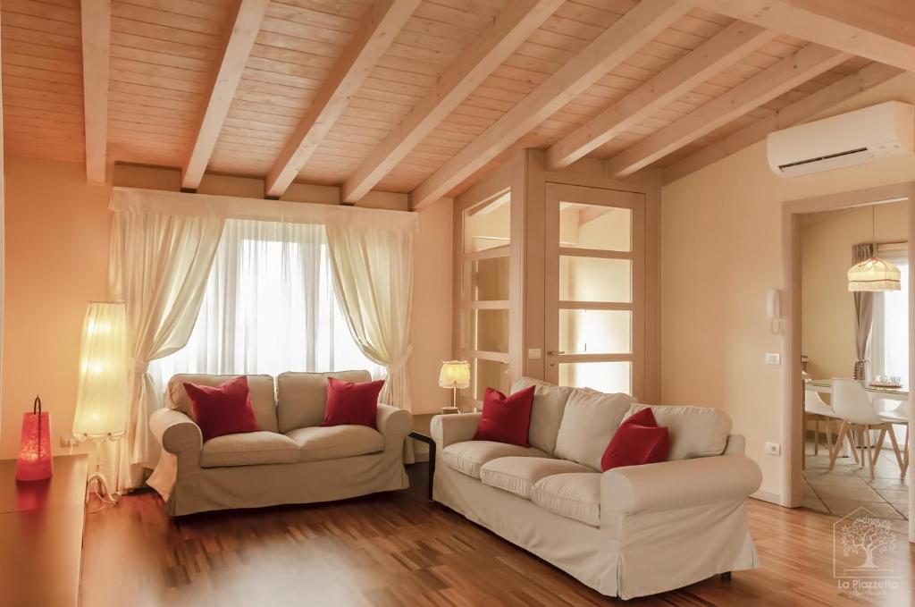 una sala de estar con 2 sofás blancos y almohadas rojas en Appartamenti La Piazzetta, en Sirmione