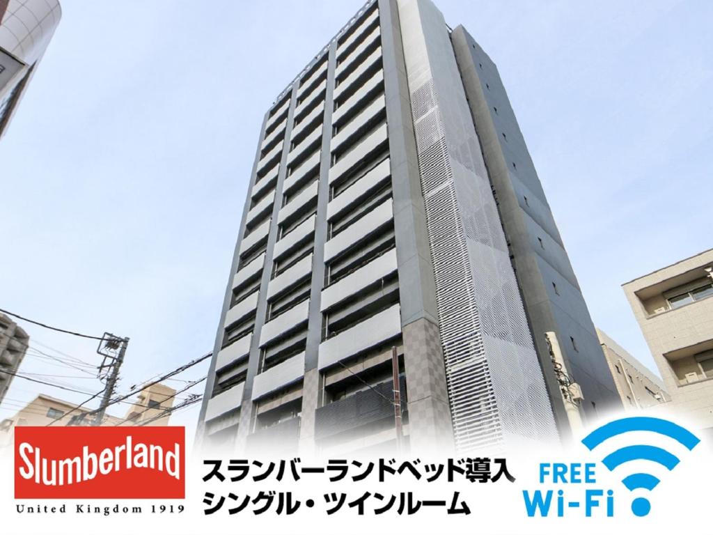 a tall building with a sign in front of it at HOTEL LiVEMAX Tokyo Ayase-Ekimae in Tokyo