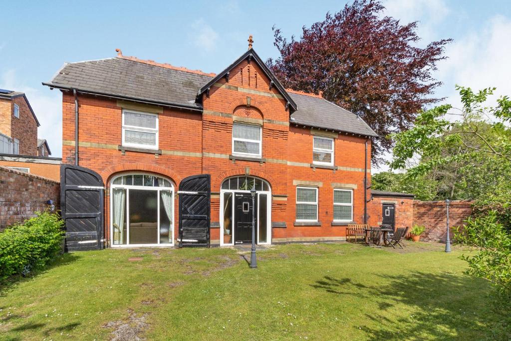 an orange brick house with a grass yard at Southport Coach House in Southport