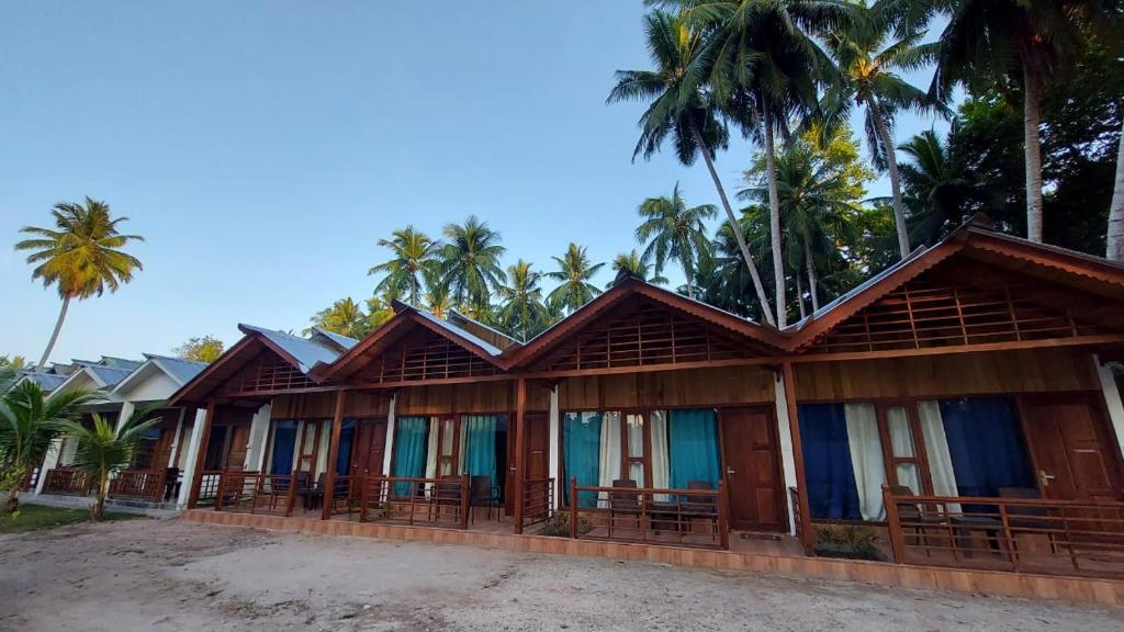 a row of houses with palm trees in the background at Lemon Grass Resort & Spa in Havelock Island