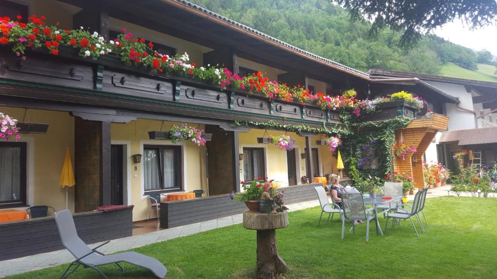 una casa con mesa, sillas y flores. en Alpen-Appartementhof, en Bad Hofgastein