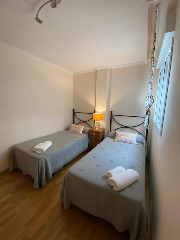 a bedroom with two beds and a table with a lamp at Apartamento Marexada Foz in Foz
