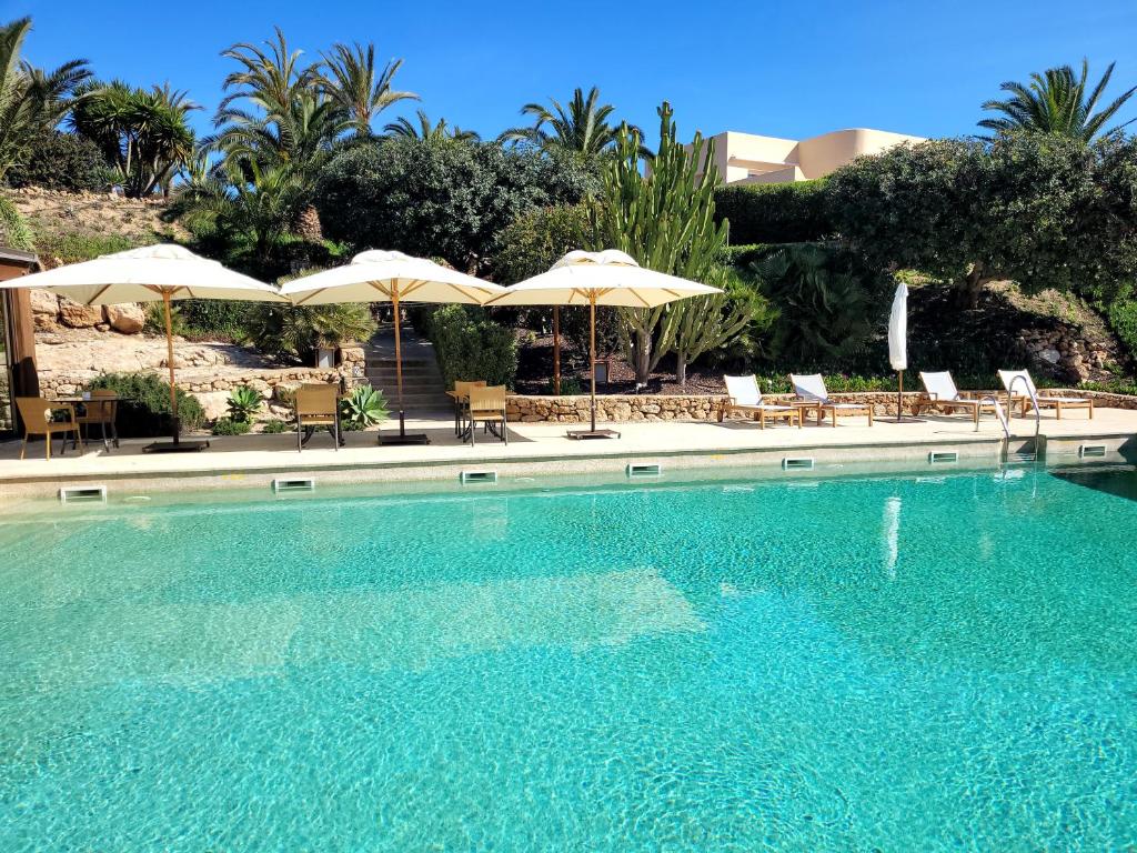 a swimming pool with chairs and umbrellas at Real Agua Amarga La Joya - Adults Only in Agua Amarga