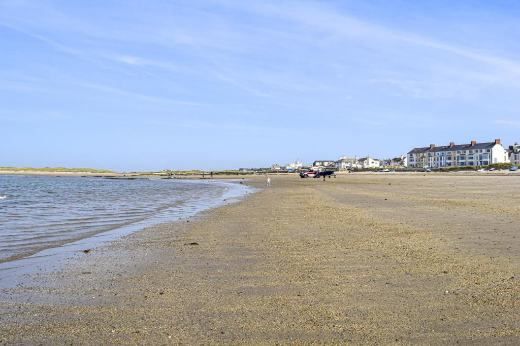 une plage de sable avec des maisons en arrière-plan et l'océan dans l'établissement Cryd Y Nant, à Rhosneigr