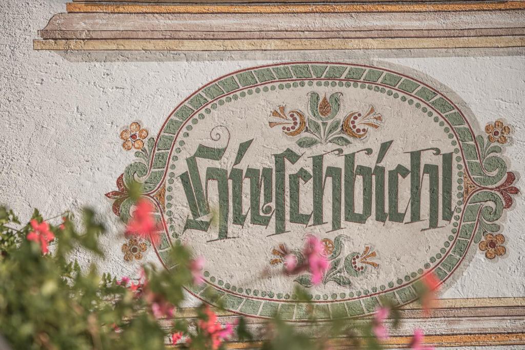 a sign on the side of a wall with flowers at Ferienwohnung Haus Hirschbichl in Berchtesgaden