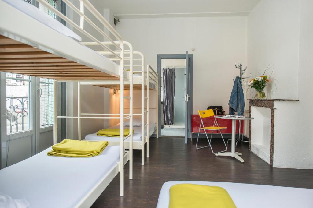 ル・ピュイ・アン・ヴレにあるGîte d'Etape des Capucinsの二段ベッドとデスクが備わるホステルドミトリールームです。