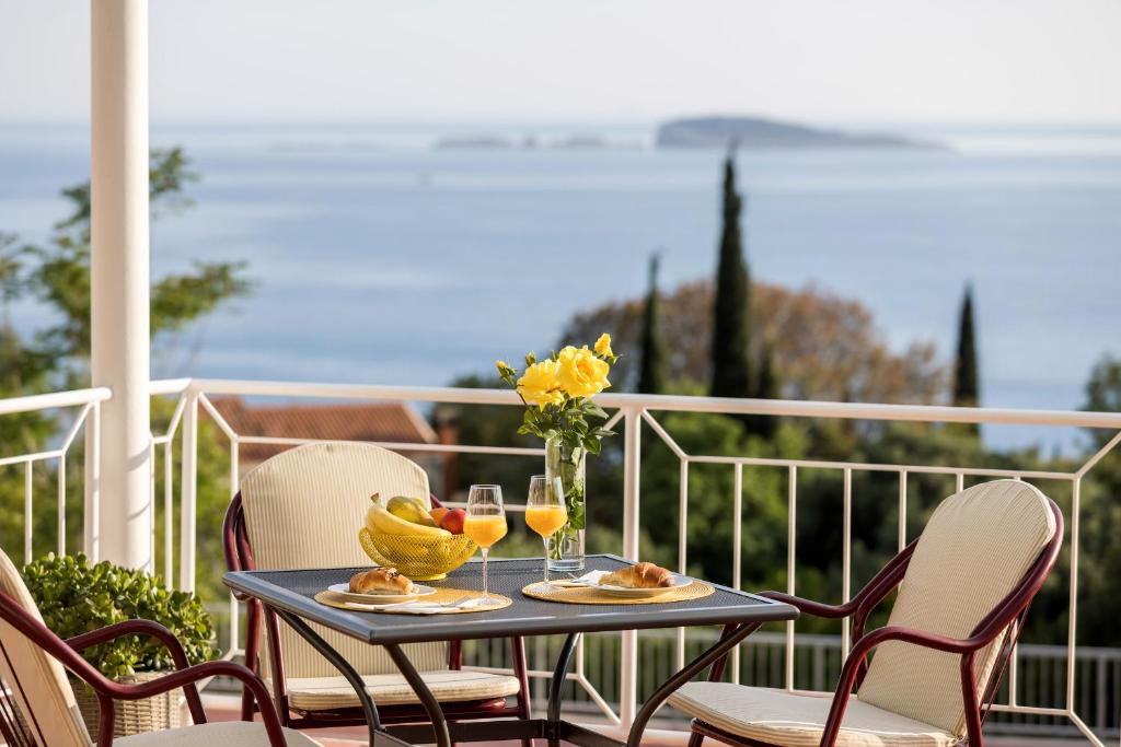 una mesa con bebidas y un jarrón de flores en el balcón en Guest House Anna en Mlini