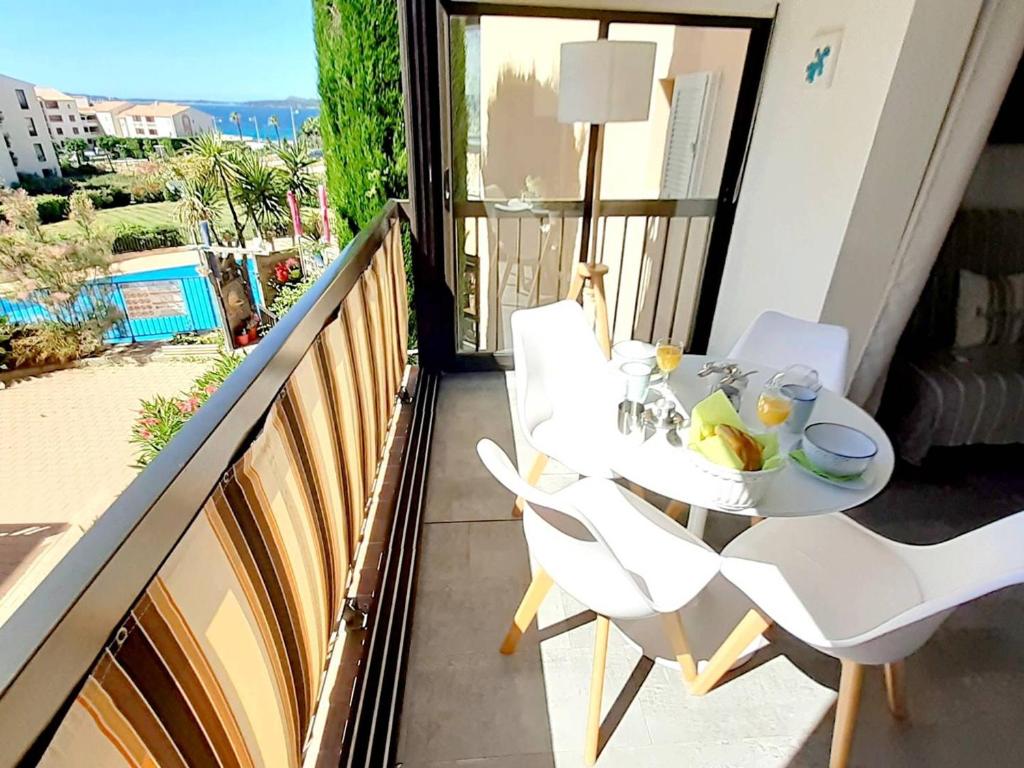 une table blanche et des chaises sur un balcon avec vue dans l'établissement T2 rénové avec piscine, parking privé et à 200m des plages - FR-1-316-274, à Six-Fours-les-Plages
