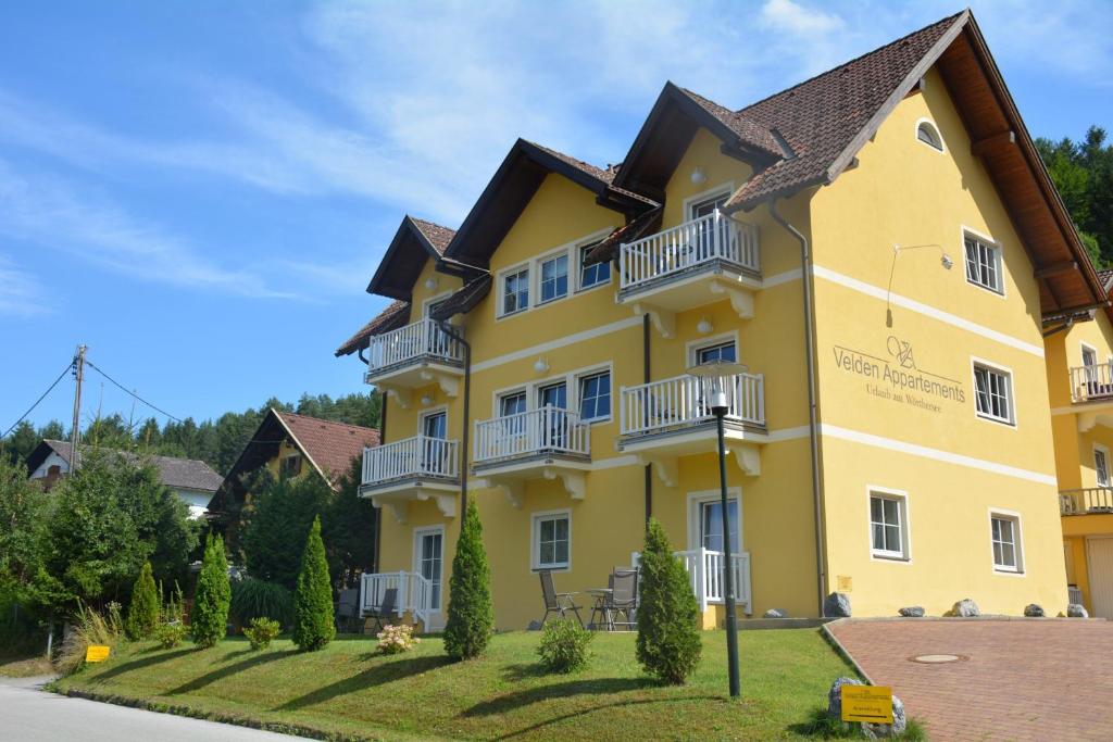 un edificio amarillo con balcones en un lateral en Velden Appartements am Wörthersee en Velden am Wörthersee