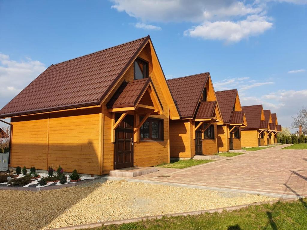 a row of wooden buildings with brown roofs at Domki Harnaś Energylandia in Przeciszów