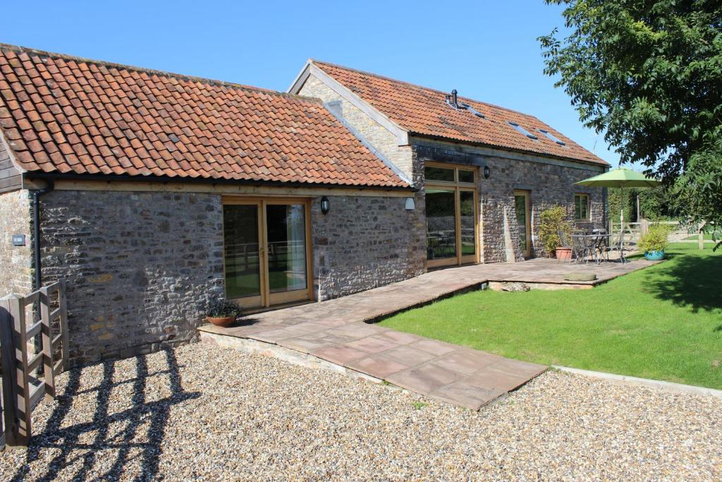 a stone house with a patio and a yard at The Barn at Freemans Farm in Alveston