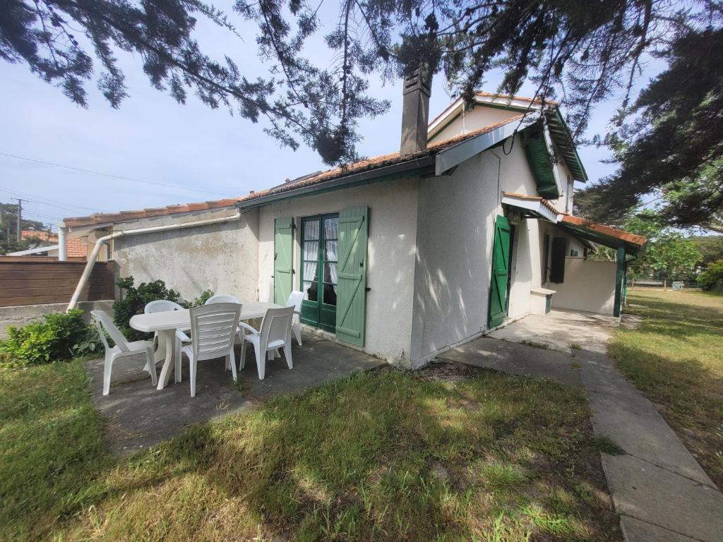 une table et des chaises devant une petite maison dans l'établissement Charmette Grand, à Mimizan