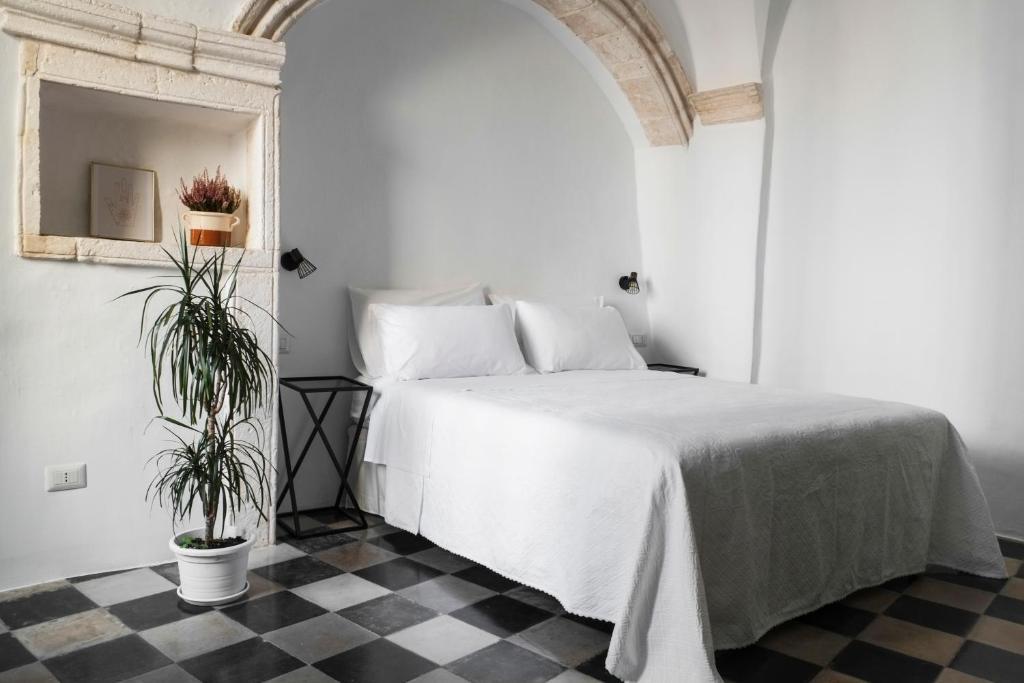 a bedroom with a white bed and a checkered floor at CALMAPIANTA home for green lovers in Putignano