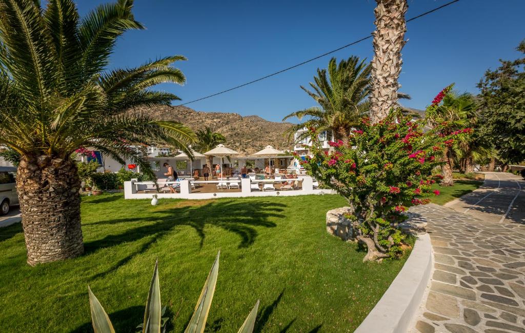 a resort with palm trees and tables and chairs at Hotel Aegeon in Mylopotas