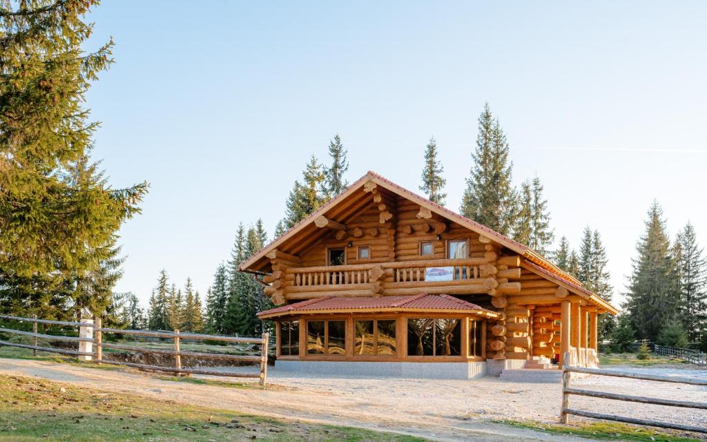 a log cabin with a fence in front of it at Casa din Deal in Mărişel