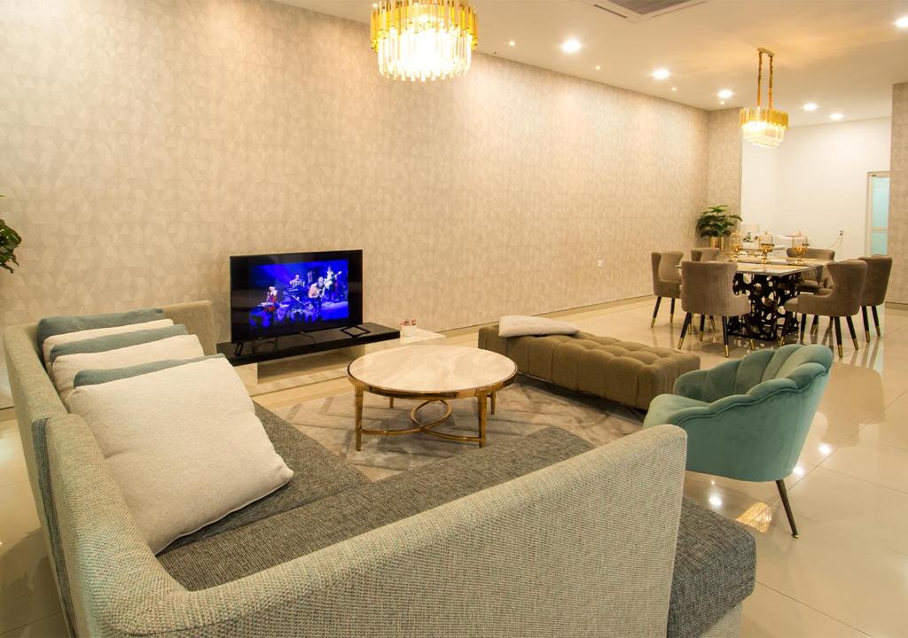 un soggiorno con divano, TV e tavolo di L.O.V.E Suite a Batu Pahat