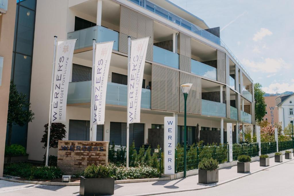 un immeuble d'appartements avec drapeaux devant lui dans l'établissement Luxury Apartment Weisses Rössl Residenzen, à Pörtschach am Wörthersee