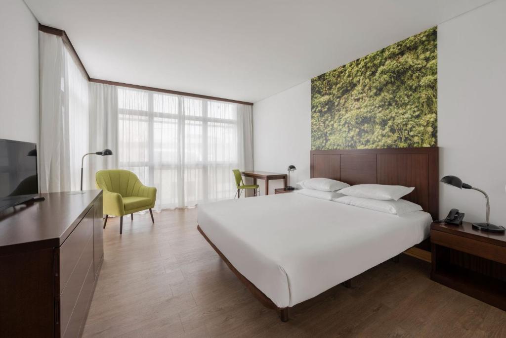 Neat Hotel Avenida في بونتا ديلغادا: غرفة نوم مع سرير أبيض كبير ومكتب