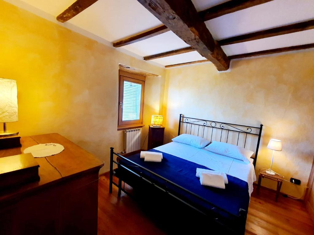 a bedroom with a blue bed and a desk and a window at Hellen Apartment in Verbania