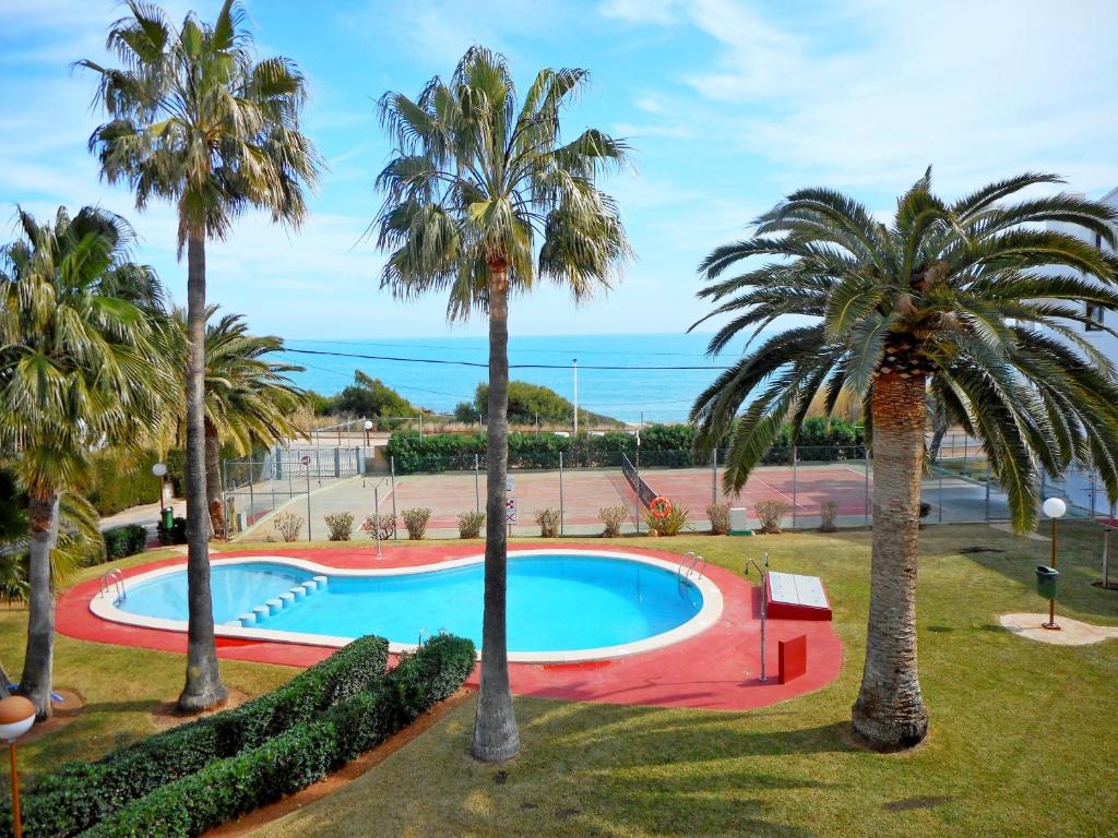 a pool with palm trees and the ocean in the background at Primera línea Playa Romana 17 - ALBERT VILLAS in Alcossebre