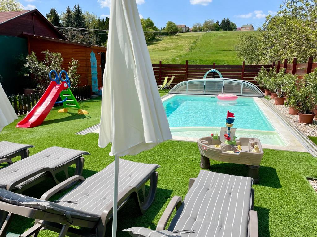 a backyard with a pool with a slide and an umbrella at Mese Panzió Zalakaros in Zalakaros