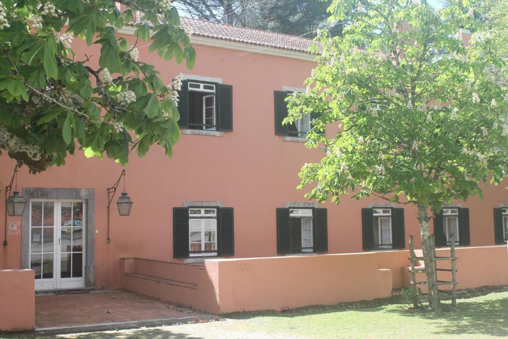 a pink building with black windows and a tree at Tapada Nacional de Mafra in Mafra